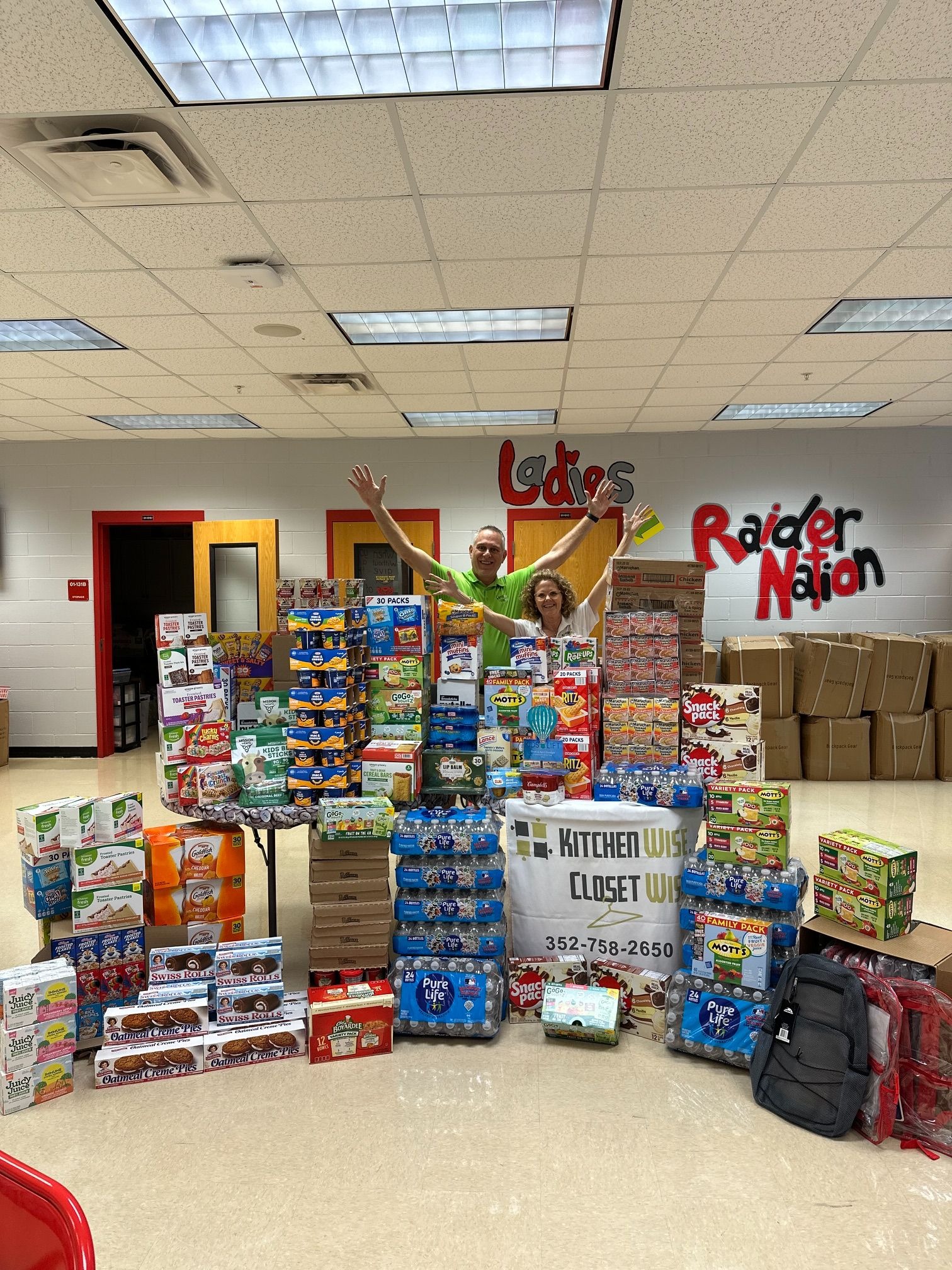 a pile of food donations with the team holding their hands up in the background